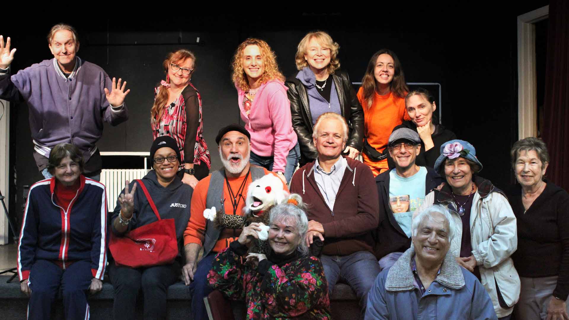 Group of actors on stage smiling.