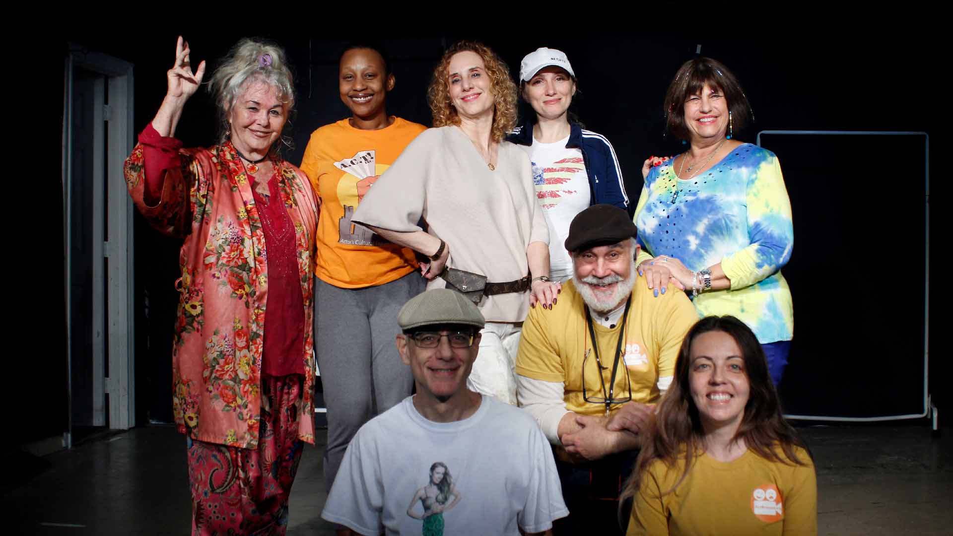 Group of actors on stage smiling.