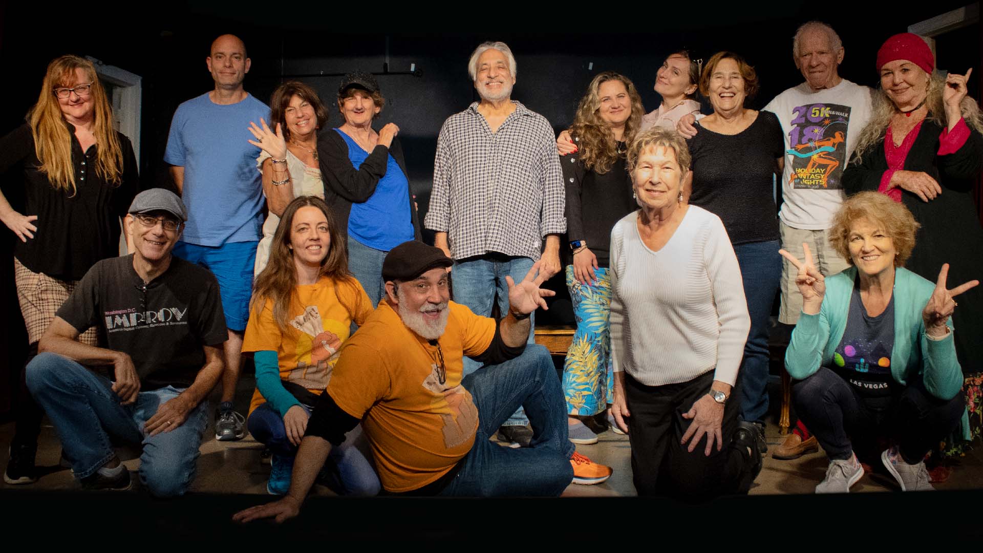 Group of actors on stage smiling.