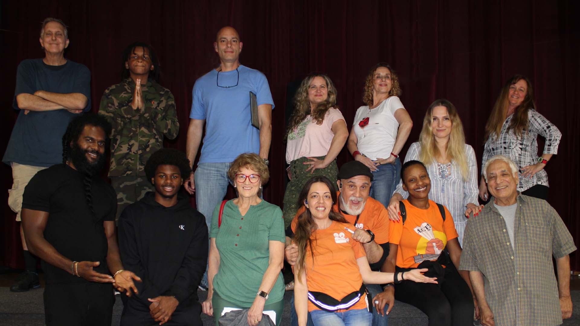 Group of actors on stage smiling.
